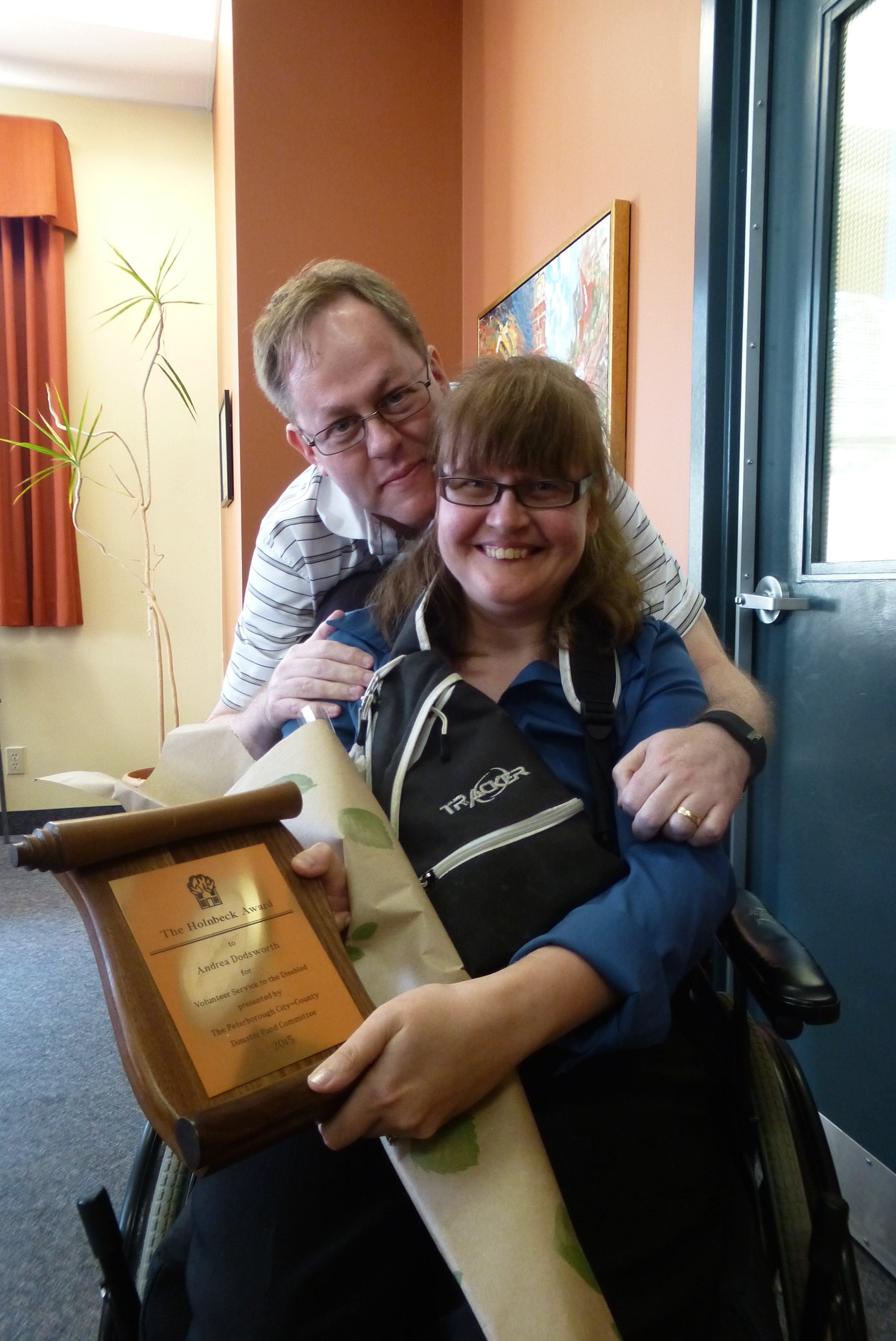 Photo of Andrea Dodsworth proudly displaying her Holnbeck Award with her husband Marc.