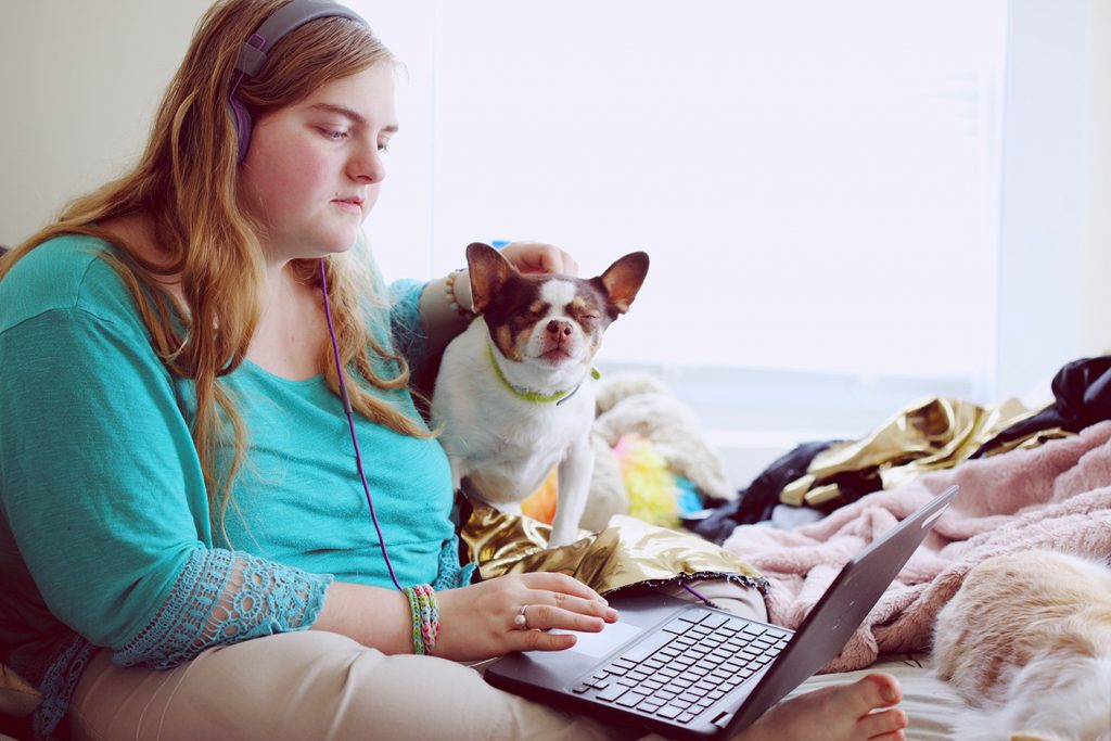 Girls with headphones on computer beside dog